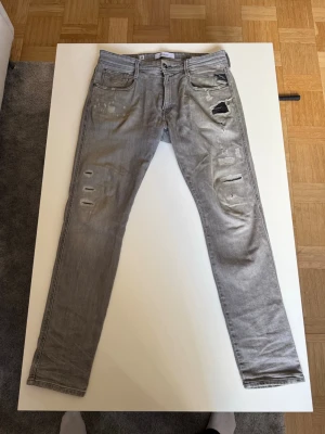 Grå jeans från Replay med slitningar - Säljer dessa riktigt feta Replay anbass jeansen. Dom har riktigt snygga slitningar och är perfekta nu till hösten. Priset ej hugget i sten, hör av dig vid frågor!