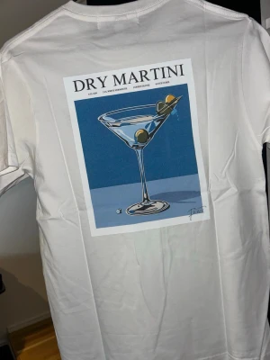 T-shirt med tryck  - Säljer en stilren och snygg T-shirt med tryck från Fiore Studios   T-shirten är vit med ett snyggt vintageinspirerat tryck på ryggen. Enkel att matcha och passar perfekt till både jeans och shorts.  Bra kvalitet och håller länge.  -Kolla min profil för mer liknande tröjor med andra motiv. -Om du hittar andra tröjor i profilen som du tycker om, skriv till mig så får du ett ”paketpris”   Storlek: S Aldrig använd. Den har bara legat i garderoben i ett år.