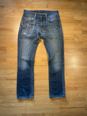 Levis 527 jeans - Säljer ett par klassiska blå levis 527 med fem fickor. Jeansen har en snygg tvättad look och kontrastsömmar. Tillverkade i slitstarkt denimtyg, perfekta för en avslappnad och tidlös stil.
