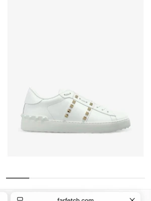 Valentino skor - Stilrena vita sneakers i läder med coola guldfärgade nitar längs snörningen och en chunky platåsula med mönstrad kant. Skorna har en klassisk låg silhuett och minimalistisk design som passar till det mesta.