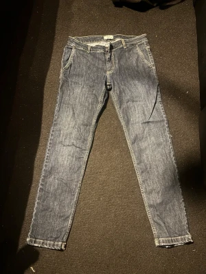 Blå smala jeans med vita sömmar libero Milano - Ett par klassiska blå jeans med smal passform och vita kontrastsömmar. Jeansen har fem fickor, bälteshällor och dragkedjegylf. Materialet är denim i bomull och passformen är rak med något smalare ben.