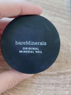 bareMinerals Original Mineral Veil puder - Säljer ett bareMinerals Original Mineral Veil i löspuderformat. Kommer i en rund svart burk med transparent lock inuti. Pudret är ljust och ger en matt finish. Perfekt för att fixera makeup och ge en naturlig look.