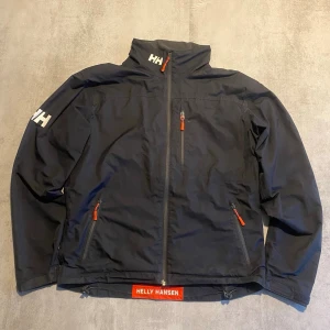 Svart Helly Hansen jacka  - Jag Säljer en fet vindjacka  från helly hansen | skicket på tröjan är bra 8/10 | storlek L| ny pris 2500: mitt pris är 999 | skriv vid frågor och funderingar  