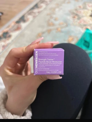 Ole Henriksen Strength Trainer 7ml - Ole Henriksen Strength Trainer Peptide Boost Moisturizer i en lila förpackning, 7 ml. Ansiktskräm med veganska peptider, ceramider och kollagen som stärker hudbarriären och återfuktar. Perfekt storlek för att testa eller ha med på resan.