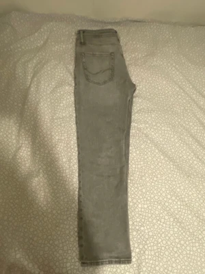 Gråa  jeans - Säljer ett par gråa regular/clark jeans med klassisk femficksdesign och smal passform. Jeansen har en enkel bakficka och raka ben. Perfekta till en avslappnad stil och passar till det mesta i garderoben.