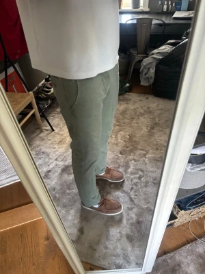 Ljusgröna chinos med rak passform - Säljer ett par ljusgröna chinos med rak passform och klassiska sidfickor. Byxorna har en enkel design utan synliga loggor och är tillverkade i ett mjukt bomullstyg som känns bekvämt. Perfekta för dig som gillar en clean och avslappnad stil.