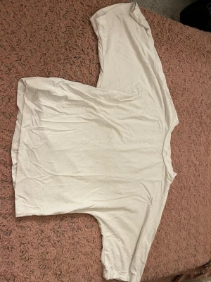Vit oversized t-shirt - En enkel vit t-shirt med oversized passform och korta ärmar. T-shirten har en klassisk rund halsringning och är gjord i mjukt material, perfekt för en avslappnad stil.