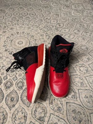 Adidas D Rose 773 IV Basketball Shoes - Säljer ett par snygga basketskor i rött och svart med vita sulor. Skorna har högt skaft, svarta snören och detaljer som '773' på tån samt en logga på plösen. Ovandelen är i syntetmaterial med ventilerande mesh på sidorna. Perfekta för basket eller streetwear. Adidas D Rose 773 IV Basketball Shoes, storlek 48, fraktar samma dag eller dagen efter :) 