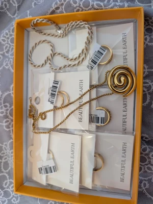 Smyckes packet i guld och silver  - Spiralformat halsband i guld. Kedjan är tunn och matchar hängets metalliska look. Halsbandet är av kirurgiskt stål och tål värme samt vatten.Säljer ett stilrent halsband med tvinnad kedja i silver.925 (92,5 pure silver) märkt klassisk design med rundad form. 42-43 cm full längd och 21-22 cm stängd, perfekt för att ge en clean och modern vibe till din outfit. Resten är från beautiful earth, en av ringarna är två och går att ha var för sig! Skriv för frågor eller fler bilder.