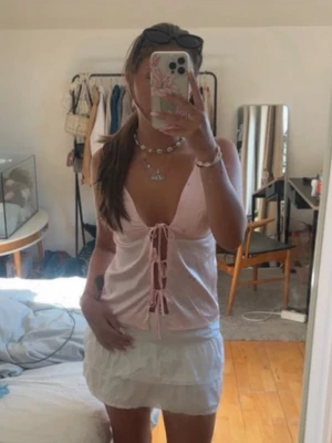 Ljusrosa linnetopp med snörning - Söt ljusrosa linnetopp med smala axelband och djup v-ringning. Toppen har snörning framtill som ger en trendig och feminin look. Perfekt för varma dagar och enkel att styla med kjol eller jeans. Säljer då den har blivit för liten för mig💗