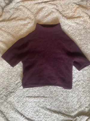 Vinröd stickad tröja Gina Tricot - Mysig vinröd stickad tröja från Gina Tricot med hög hals och halvlånga ärmar. Tröjan har en enkel, rak passform och är tillverkad i ett mjukt material som känns skönt mot huden. Perfekt för lager på lager och en stilren look.