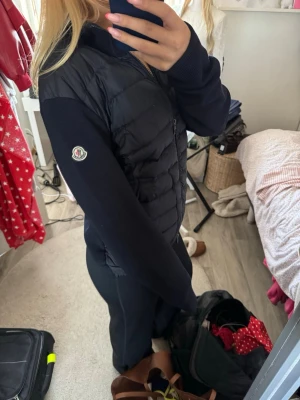 Svart cardiganjacka från Moncler - Snygg marinblå cardiganjacka från Moncler med quiltad, vadderad framsida och stickade ärmar. Dragkedja framtill och diskret Moncler-logga på ena ärmen. Perfekt för lager på lager och ger en sportig men ändå clean look. Jackan är i storlek m och jag är 167cm och bär vanligtvis S💗