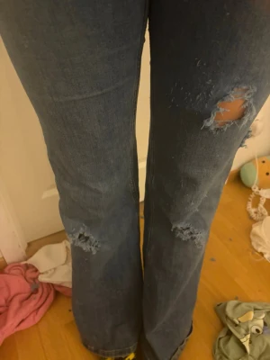 Blå slitna bootcut jeans - Blå jeans med sydda hål, De har hål på baksidan men ifall nån kan sy kan man ju laga de! Därför säljs de så billigt. Från cheap Monday storlek 29/32 