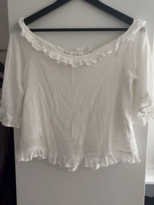 Vit volangblus från Lindex - Söt vit blus från Lindex. Trekvartsarmar och går att ha off shoulder eller inte. På framsidan har den ett extra lager så den är inte genomskinlig. Går att ha bak o fram. Använd enstaka gånger. Kom gärna med prisförslag!💗