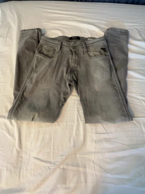 Grå slim fit jeans - Säljer ett par grå slim fit jeans med klassisk femficksdesign och dragkedjegylf. Jeansen har en snygg tvättad look och smala ben som ger en modern siluett. Perfekta för dig som gillar en stilren och enkel vardagsstil.