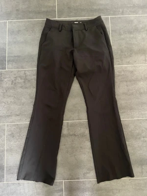 Svarta lågmidjade kostymbyxor  - Svarta lågmidjade kostymbyxor från bikbok i storlek 36 som är avklippta längst ner. Passar mig som är 155 cm. Säljer även ett par likadana i storlek 34.