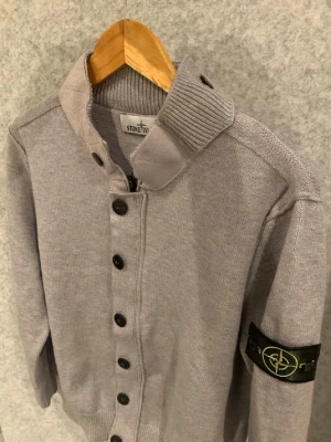 Grå stone Island cardigan  - Tjena säljer denna skitsnygga Cardigan från stone island, står M på den men passar S. Har både dragkedja och knappar, tröjan är i utmärkt skick, jävligt snygg, skriv gärna vid intresse!