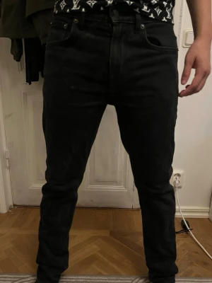 Svarta raka jeans herr - Säljer ett par svarta jeans med rak passform och klassisk femficksdesign. Jeansen har normal midja och är tillverkade i denim med lätt stretch för skön känsla. Perfekta till en avslappnad stil och funkar året runt.