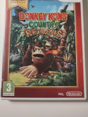 Donkey Kong Country Returns Wii - Donkey Kong Country Returns till Nintendo Wii. Färgglad spelbox med Donkey Kong och Diddy Kong i djungelmiljö. PAL-version och del av Nintendo Selects-serien. Perfekt för dig som gillar plattformsspel och klassiska äventyr. Skivan har spår av användning, se bilder.