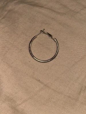 Silverfärgade hoops örhängen - Säljer ett par klassiska hoops i silverfärg. De är runda och har enkel, stilren design med smal metall och praktiskt lås. Perfekta för dig som gillar minimalistiska accessoarer och vill ha något som funkar till många olika looks.