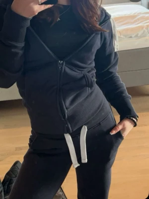 Russemerch sett (båda delarna kommer med)  - Säljer ett mörkblått loungewear-set med hoodie och matchande byxor. Hoodien har dragkedja, fickor och ribbade muddar. Byxorna har resår i midjan och vita dragsnören. Perfekt för chill dagar hemma eller när du vill vara bekväm. Båda delarna är xxs. Är ca 160.