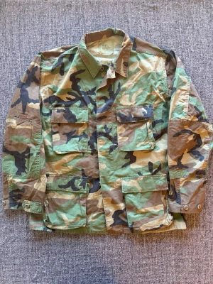 US Army BDU Woodland Combat Jacket - Säljer nu denna klassiska US Army BDU Woodland Combat Jacket | st Medium-Regular (M/R) ~ passar ca 175–185cm | äkta militärjacka i klassiskt woodland camo | tillverkad i slitstark 50/50 bomull/nylon | perfekt för vintage, streetwear och outdoor. Kan även gå ner lite i pris vid snabb affär🍁🫶