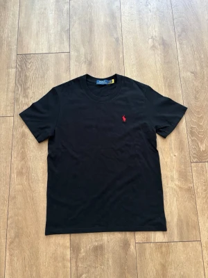Svart Ralph Lauren T-Shirt med röd logga - Strl S 🔥 - Säljer en snygg svart t-shirt från Polo Ralph Lauren med broderad röd hästlogga på bröstet. Skön kvalitet och en tidlös klassiker som passar till det mesta.  Märke: Polo Ralph Lauren  Storlek: S  Färg: Svart / Röd logga  Skick: Fint skick Skickas spårbart eller hämtas enligt överenskommelse. Skicka ett DM om du har några frågor eller vill ha mått! 📦✨ 