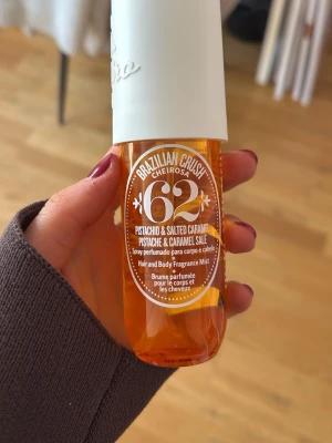Brazilian Crush Cheirosa 62 mist - Fräsch och söt doftmist från Sol de Janeiro, Brazilian Crush Cheirosa 62, med noter av pistage och salt karamell. Flaskan är genomskinlig orange med vit kork och rymmer 90 ml. Passar både kropp och hår för en tropisk känsla. Har kvar ca 80 ml