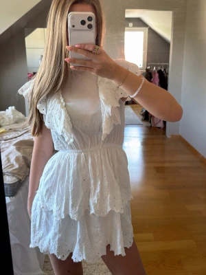 Vit kort klänning från H&M Divided - Söt vit kort klänning från H&M Divided med volangdetaljer och broderad spets. Köptes förra sommaren och är använd fåtals gånger🤍
