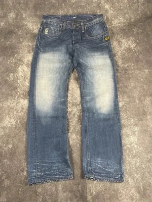 Ljusblå G-Star vintagejeans för herrar i storlek W31 L34 - Snygg 2000-tals tvätt och rak benlinje ger en skön Y2K-känsla. Snyggt linjeformat slitage.  Skick: 9,5/10  Midja: 41 cm Benslut: 20 cm Lår: 32 cm Totallängd: 107 cm Måtten finns även på bilderna  Skickas inom ett dygn På min profil finns fler G-Star-jeans