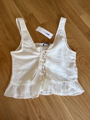 Topp Gina tricot stl M - Helt ny topp med snörning från Gina tricot i storlek M.  Blusmaterial, perfekt för varma dagar. Köptes för 299 kr. 