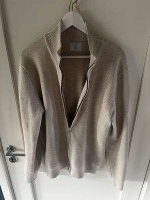 Beige fullzip Bläck - Skick: 10/10.                                        Storlek: Medium.                              Snygg beige ziptröja från Bläck i mjukt material.  Perfekt för lager på lager och enkel att matcha med olika outfits, dels mer uppklätt men även mer casual. Hör av er vid frågor!                Mvh Axel