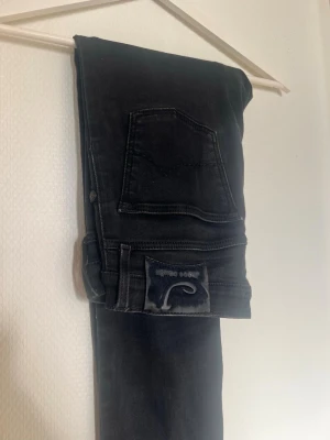 Svarta raka jeans från Pepe Jeans - Snygga svarta jeans från Pepe Jeans med klassisk femficksdesign och raka ben. Jeansen har en mörk tvätt och ett diskret läderpatch med logga bak. Perfekta till en avslappnad streetstyle-look.
