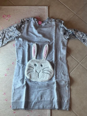 Grå pyjamas med kaninmotiv - Supergullig grå pyjamas med långa ärmar och ett stort kaninansikte framtill i mjukt material. Ärmarna har ett lekfullt djurmönster i svart och vitt. Perfekt för dig som gillar söta detaljer och vill sticka ut lite extra.