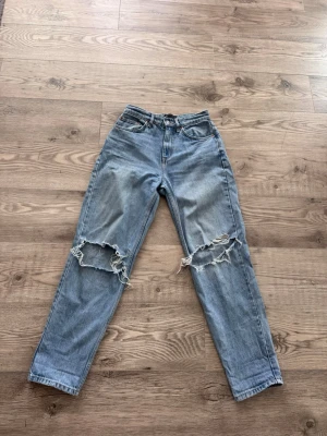 Blåa jeans -Asos - Säljer ett par blå jeans från Asos med hål på knäna. Säljer då de inte är min stil längre. Storleken är 26/28 -petite och passar bra i längd om man är runt 160. Meddela för frågor:)