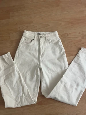 Vita high waist raka jeans från gina - Säljer ett par vita jeans med hög midja och raka ben. Klassisk femficksmodell med knapp och dragkedja framtill. 