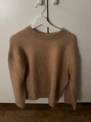 Beige stickad tröja med rund hals - Mysig beige stickad tröja med rund halsringning och långa ärmar. Ullmaterial, Storlek S men väldigt stor i storlek. Aldrig använd endast testad. 