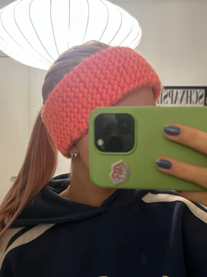 Stickat pannband korall - Chunky stickat pannband i neonrosa/korall som jag stickat själv🩷🧡Då jag gjort den själv är den lite ojämn där bak, däremot kan man justera själv hur den ska sitta så det inte syns. Värmer jättebra då det är tjockt och innehåller ull. Passar jättebra under vintern eller i fjällen!