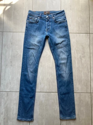 Blå slim fit jeans från Morris - Snygga blå slim fit jeans från Morris med klassisk femficksdesign och ljusa slitningar framtill. Jeansen har normal midja, raka ben och är tillverkade i mjukt denimtyg. Perfekta för en avslappnad och trendig look. Vid frågor och funderingar skriv gärna. Strl 31/34!