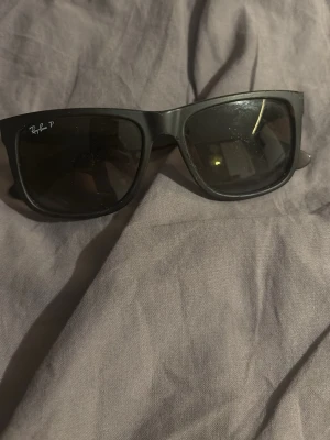  Ray-Ban solglasögon  - Snygga svarta solglasögon från Ray-Ban med bred båge och mörka glas. Klassisk fyrkantig form som passar till de flesta stilar. Perfekta för soliga dagar och ger en cool vibe.