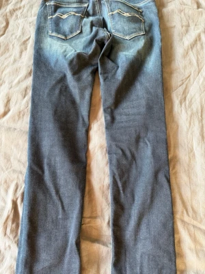 Blå raka jeans med kontrastsömmar - Säljer ett par blå jeans med raka ben och snygga kontrastsömmar på bakfickorna. Jeansen har klassisk femficksdesign och slitningar framtill för en cool, avslappnad look. Perfekta till vardagsstilen och passar till det mesta. Gör en snabb affär så kan jag säkrt gå ner lite i pris