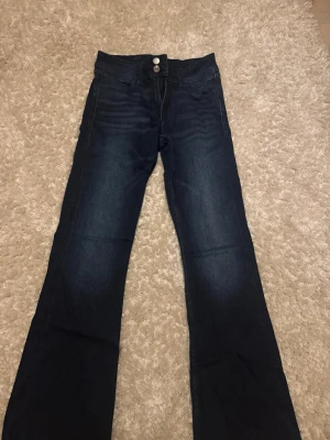 Mörkblå bootcut jeans  - Snygga mörkblå bootcut jeans med dubbla silverknappar i midjan och klassiska fem fickor. Aldrig använda endast provade. Snygga att klä upp samt använda till vardags 💕💕 Storlek 164 och passar mig som bär XS/S