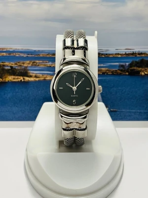 Stilren silverfärgad klocka - Snygg och stilren klocka med rund svart urtavla och silverfärgat armband i metall. Klockan har minimalistisk design med tydliga siffror och meshdetaljer på bandet. Perfekt accessoar för dig som gillar en klassisk look.Nytt batteri, säljes i befintligt skick enligt bilderna!