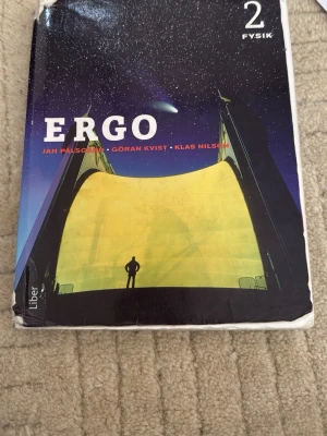Ergo Fysik 2 kursbok - Kursbok i fysik för gymnasiet, 'Ergo Fysik 2' av Jan Pålsgård, Göran Kvist och Klas Nilsson. Omslaget har en futuristisk illustration med siluett och stjärnhimmel. Boken är utgiven av Liber och har mjukt omslag.