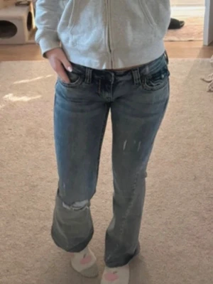 True religon jeans lågmidjade storlek 25 - Säljer dessa vackra blå lowrise äkta true religion jeans med design på fickorna!🤍 Dessa är faktiskt blåa fast lite åt det mer gråa hållet men ser gråare ut i det här ljuset🫶🏻 Jeansen är i storlek 25 vilket motsvarar ungefär XS✨ Köpt från plick för någon vecka sen men insåg att den var i fel storlek😢 Den förra ägaren hade tyvärr klippt lite vid fötterna så de skulle bli lite längre tror jag❤️ Pris kan definitivt diskuteras! Snabb leverans och det är bara att fråga om fler bilder😊