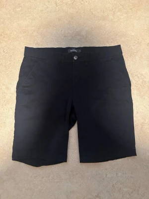 Marin blå  klassiska shorts - Snygga svarta shorts med normal passform och midwaist. De har knapp och dragkedja framtill samt sidofickor. Perfekta för sommaren och passar till det mesta. Materialet känns som bomull eller en bomullsblandning.