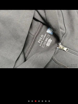 Svart hoodie från Polo Ralph Lauren - Snygg svart hoodie från Polo Ralph Lauren med dragkedja framtill och klassisk huva. Tröjan har ribbade muddar vid ärmslut och nederkant samt en liten broderad logga på bröstet. Tillverkad i mjukt bomullsmaterial för en bekväm känsla.
