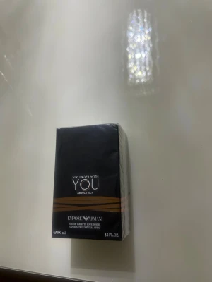 Stronger With You Absolutely parfym - En ny oöppnad parfym från Emporio Armani Stronger With You Absolutely är en parfym i en elegant svart rektangulär kartong med guldiga detaljer. Flaskan innehåller 100 ml och har en modern, stilren design som passar perfekt för dig som gillar exklusiva dofter.