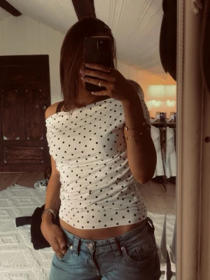 Vit prickig offshoulder topp - Super fin vit offshoulder topp med svarta prickar. Toppen är aldrig använd (endast testad) och har prislappen kvar! Orginalpris 150kr