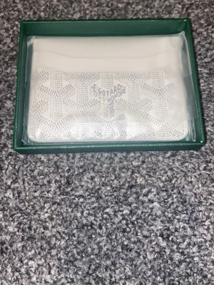 Vit kortfodral  - Säljer ett stilrent vitt kortfodral med det klassiska mönstret och loggan tryckt på framsidan. Kortfodralet har en smidig och tunn design, perfekt för att bära med sig i fickan eller väskan. Kommer i original grön ask.